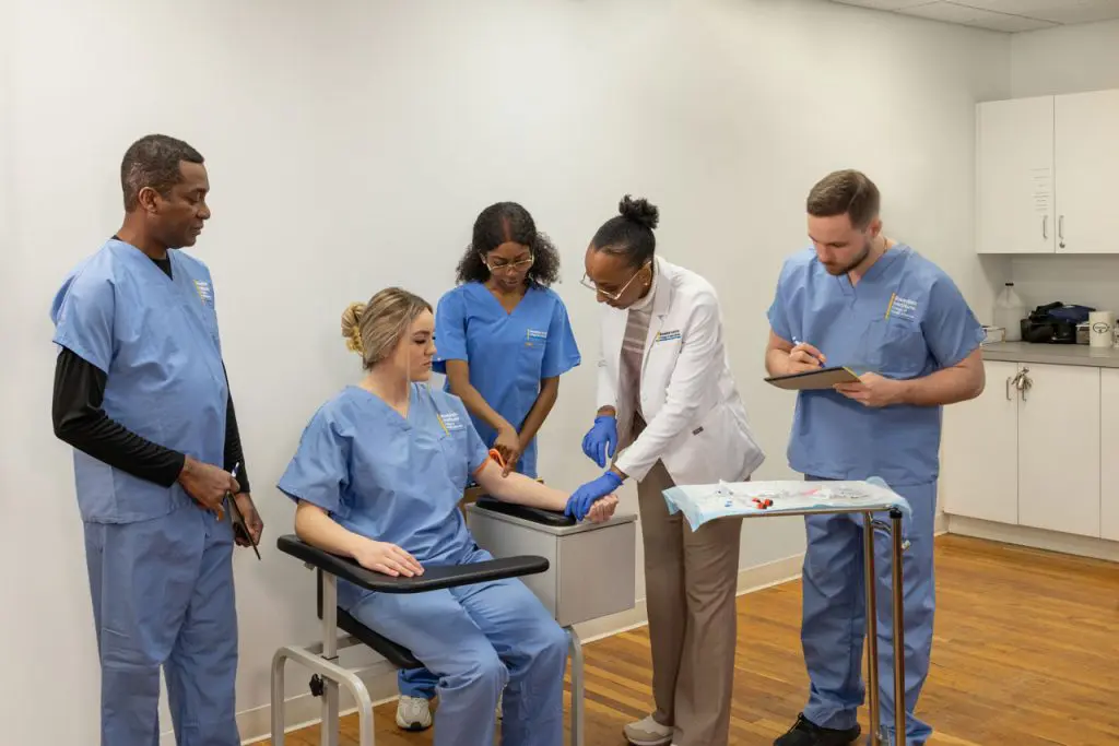 medical assistant students watching a demonstration on another student