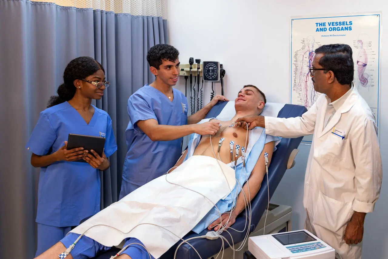 two medical assistant students working with an instructor and a patient