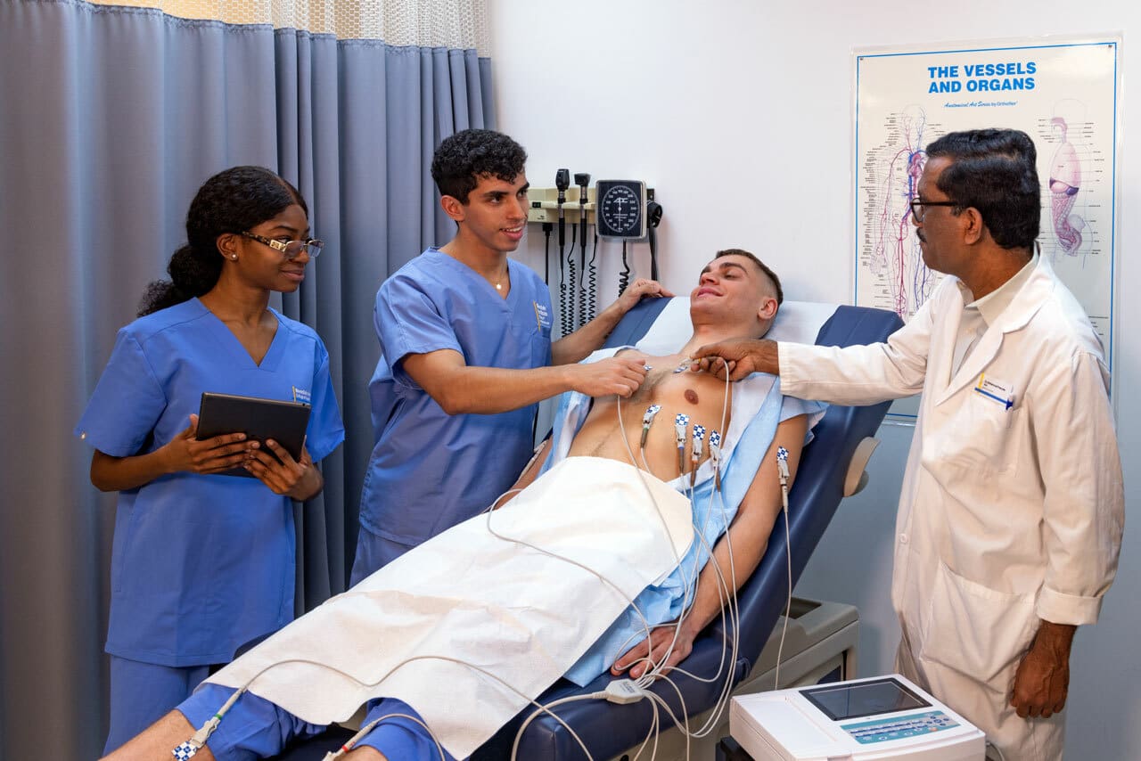 two medical assistant students working with an instructor and a patient